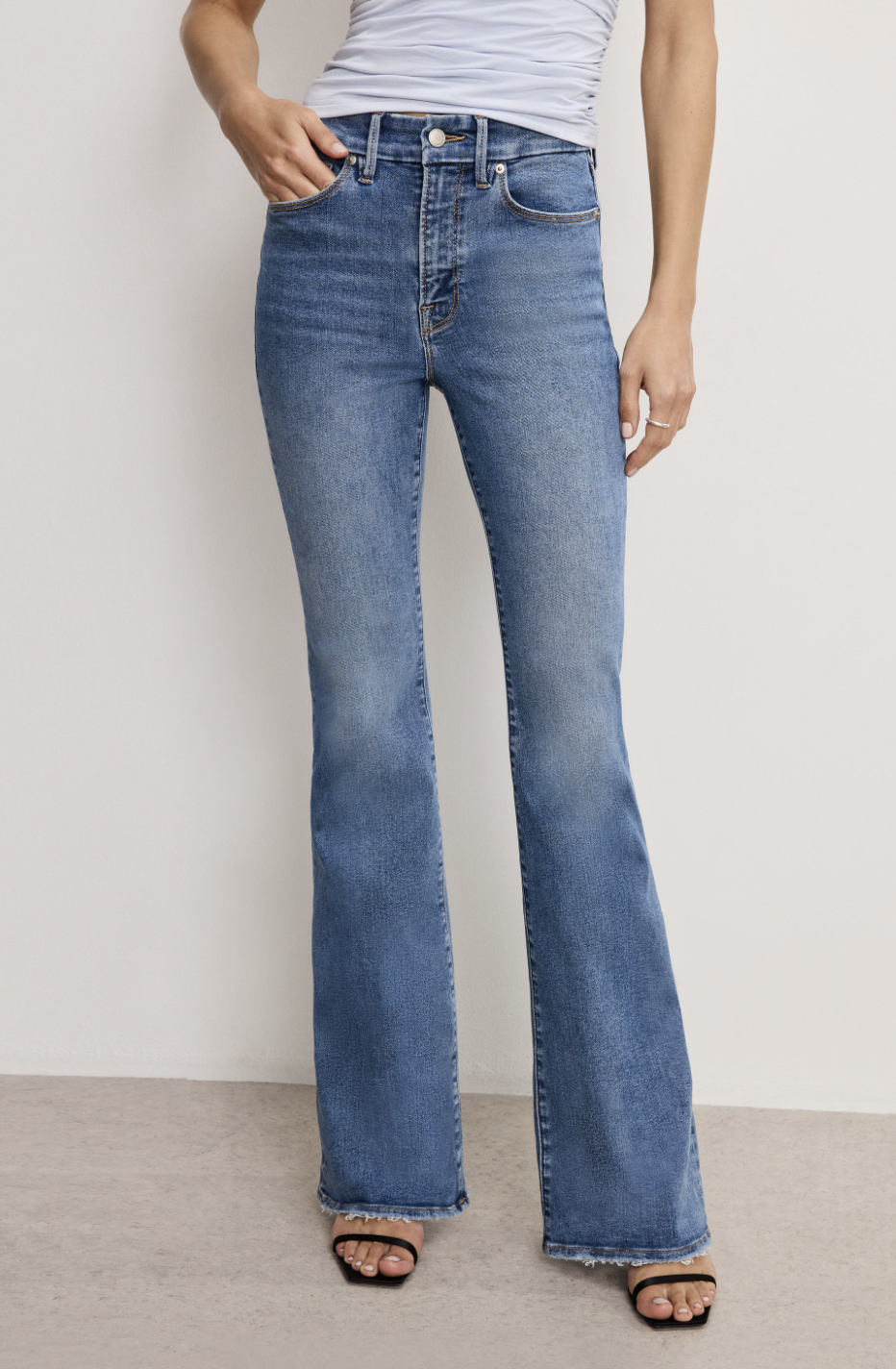 Rear view of a person wearing high-waisted flare jeans with a curved back yoke designed to lift and shape a flat bottom.