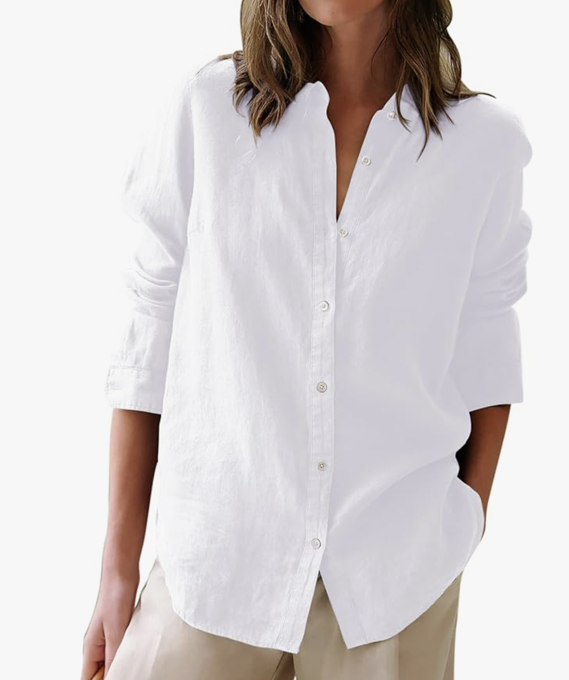 A close-up of a woman wearing a crisp white oversized linen-style button-down shirt with long sleeves rolled up, styled with tan trousers as a spring staple for women in their 60s.