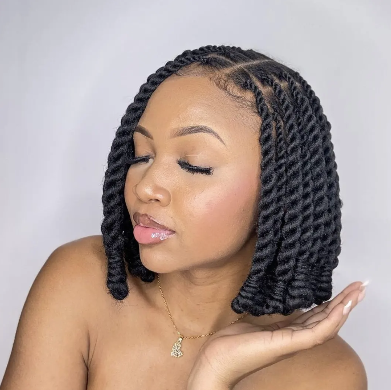 A woman with voluminous, shoulder-length Marley twists featuring a kinky, natural-looking texture and a side part.