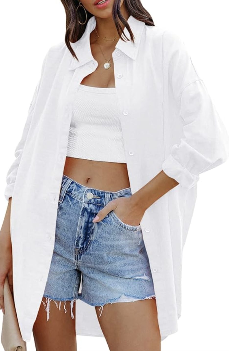 A close-up of a person wearing light-wash distressed denim shorts with a raw hem, styled with a white oversized button-down shirt.