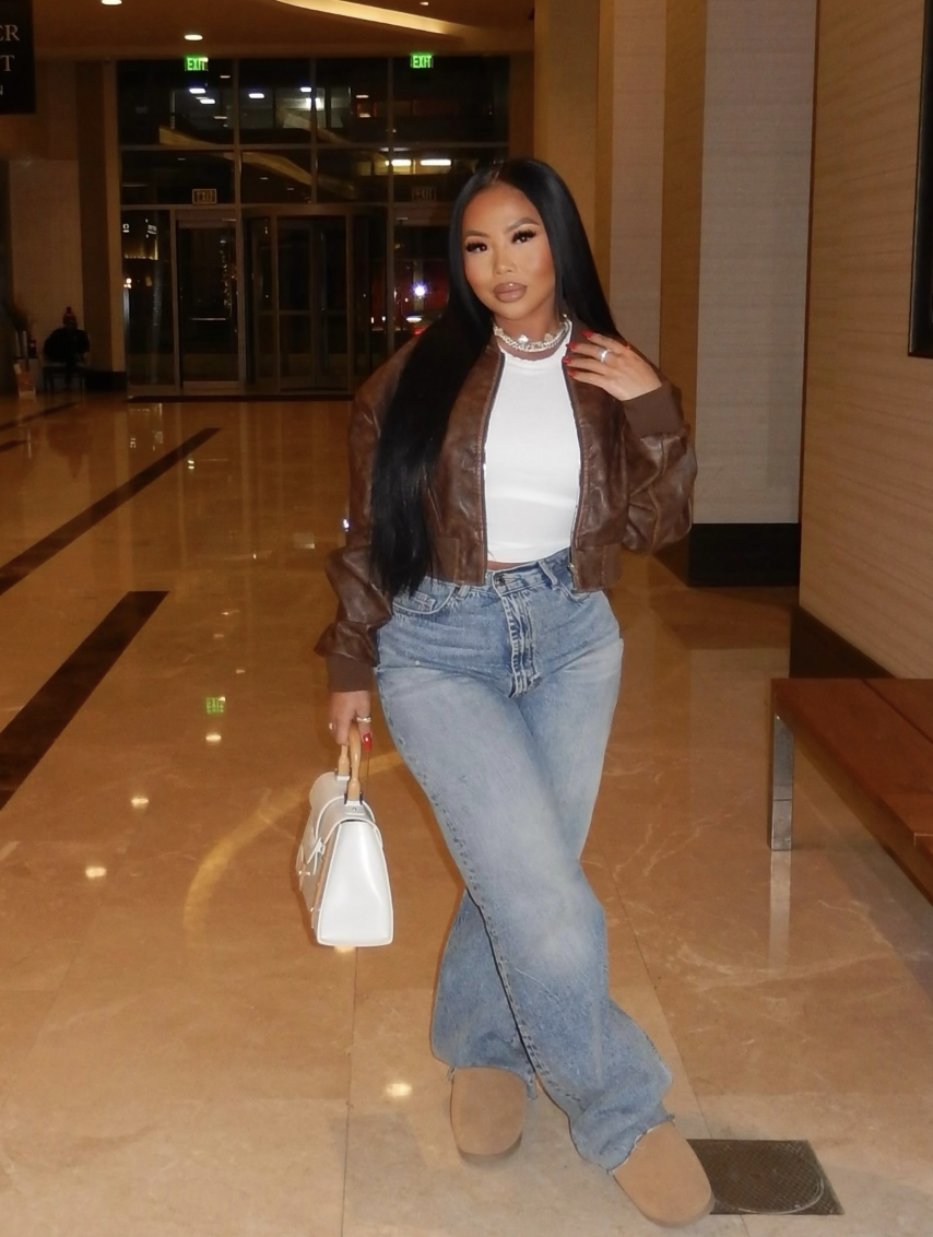 Cropped brown leather-look jacket and fitted white top with wide-leg blue jeans and chestnut boots.