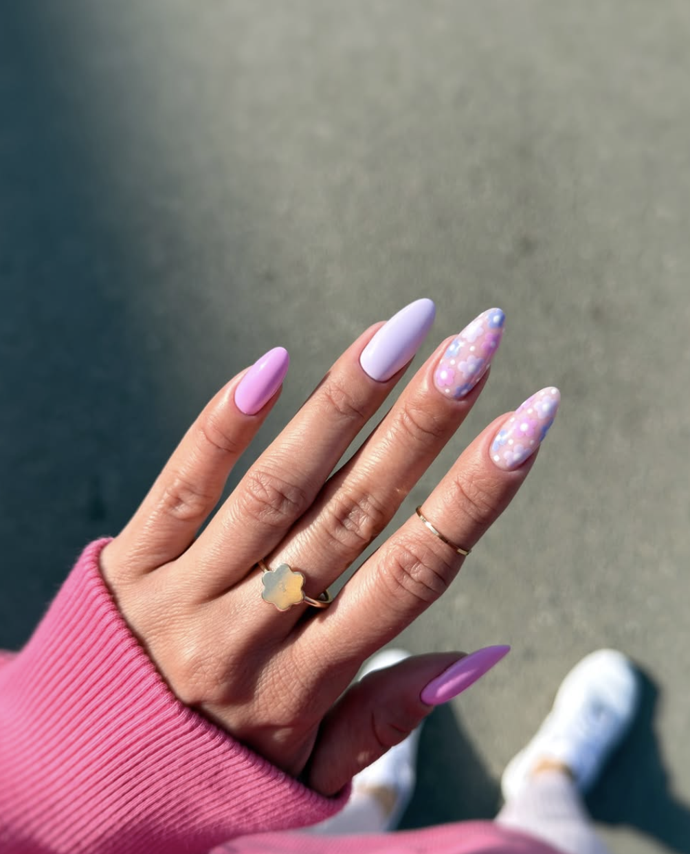 High-feminine almond nails by @gandziuchaa featuring a mix of lilac and bubblegum pink polish with multicolored pastel floral confetti accent nails.