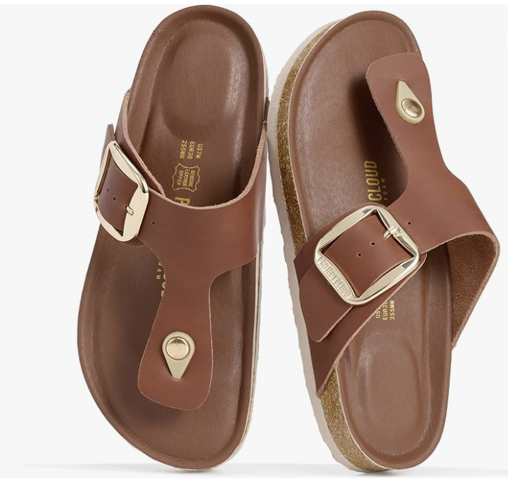 A pair of Project Cloud brown genuine leather thong sandals with a large gold buckle and cork footbed, styled as a luxury spring staple for women over 60.
