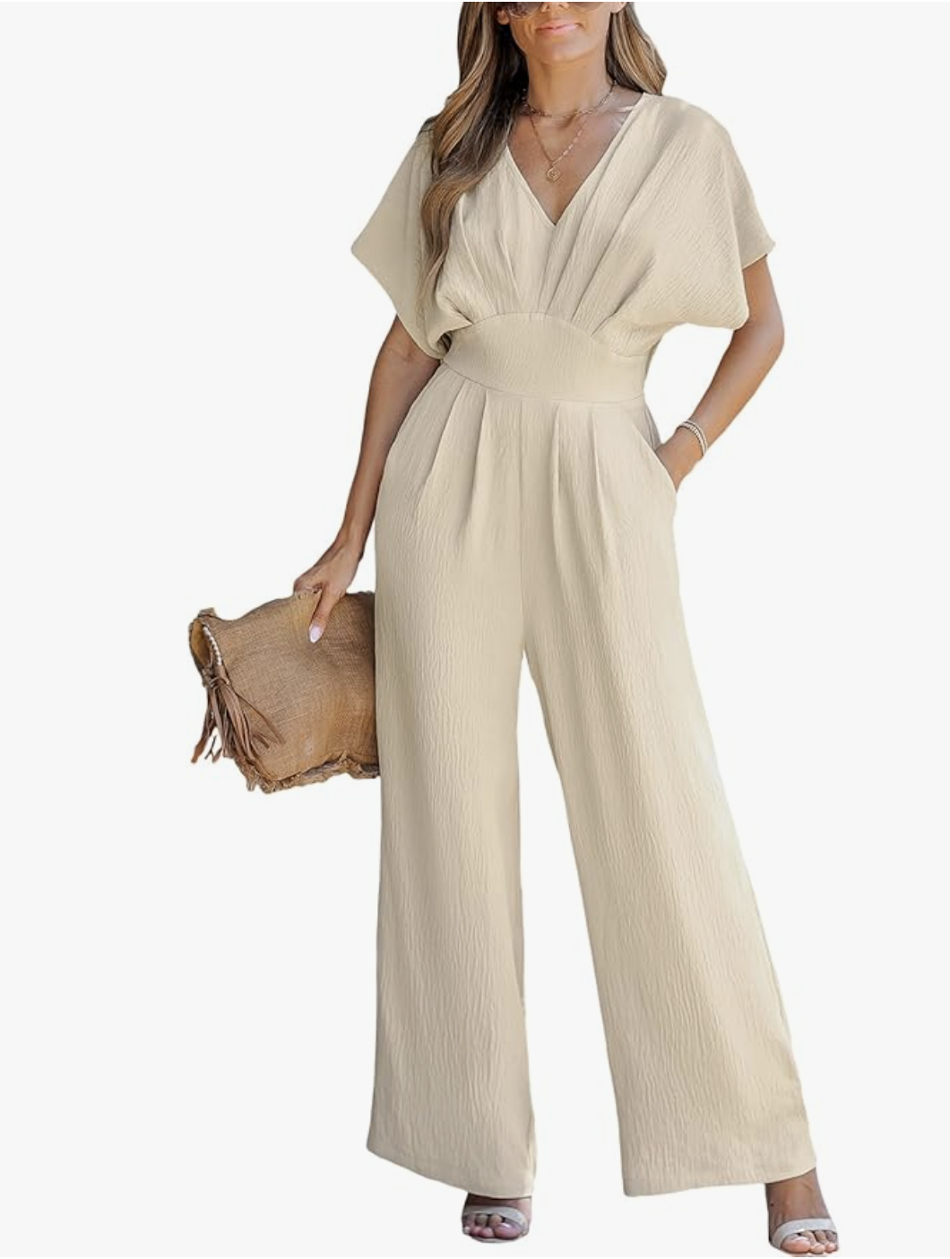 A woman wearing the CUPSHE Batwing Sleeve Jumpsuit in beige, featuring a plunging V-neckline, pleated waist, and a straw clutch, styled as an elevated Amazon spring outfit.
