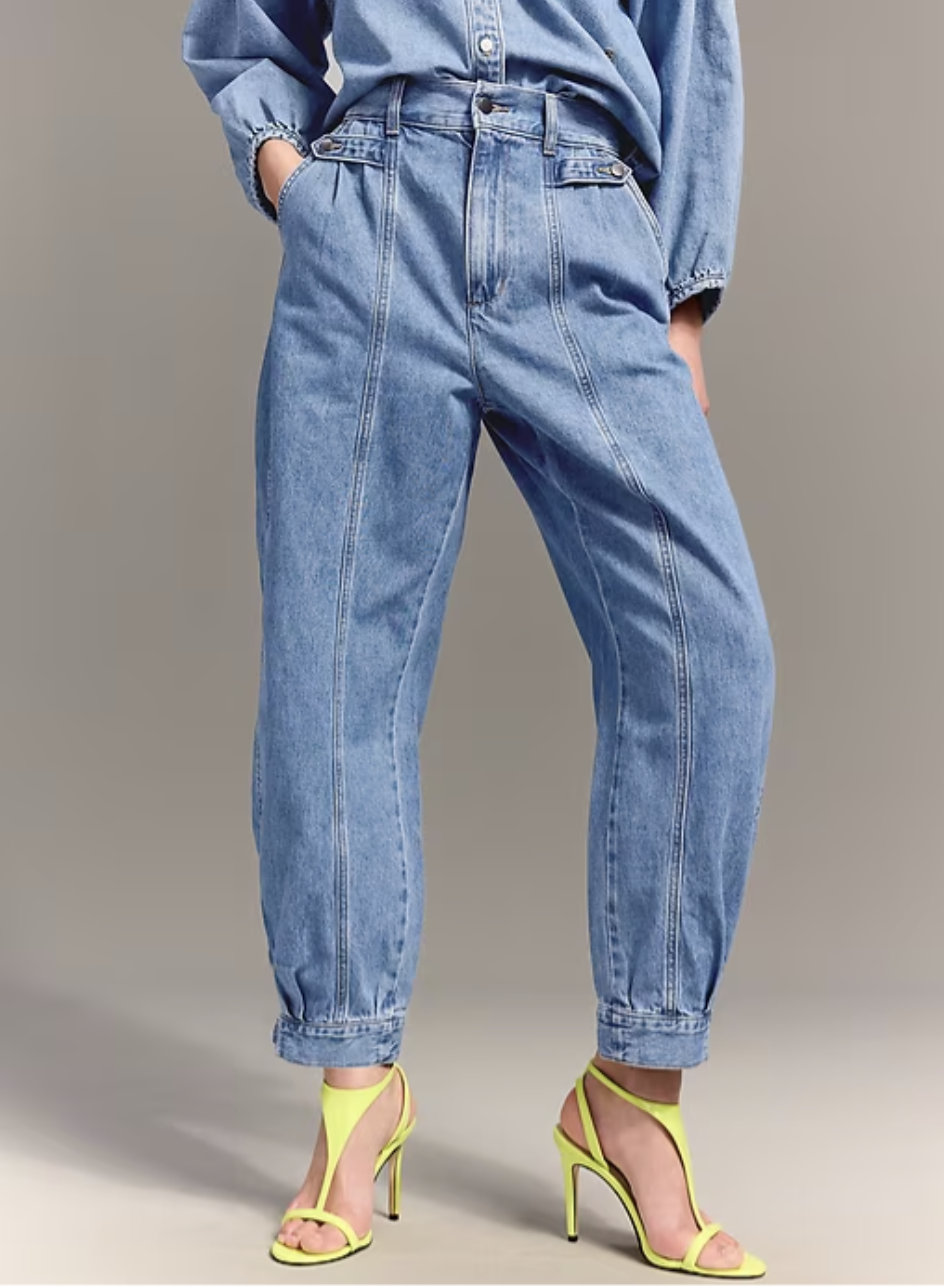 Full length view of Old Navy x Christopher John Rogers high-waisted barrel jeans in a medium wash denim paired with lime green strappy sandals.
