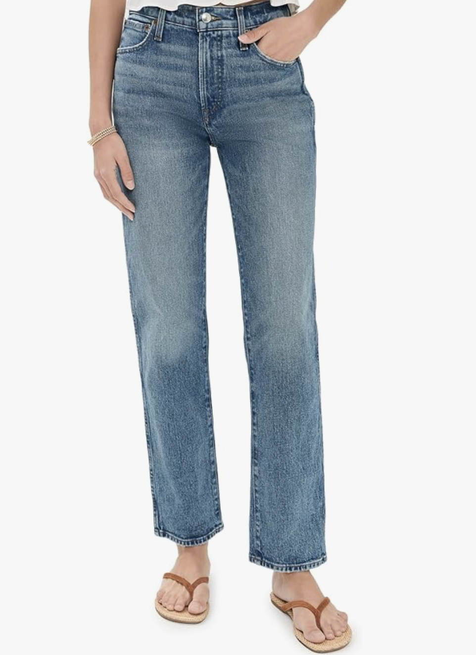 A woman wearing Madewell Longline Straight Jeans in a light blue wash, paired with tan flip-flop sandals.