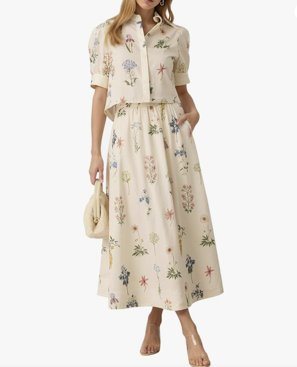 Close-up of a cream-colored matching maxi skirt and short-sleeve button-down set with an all-over muted floral print, styled with clear heeled sandals.
