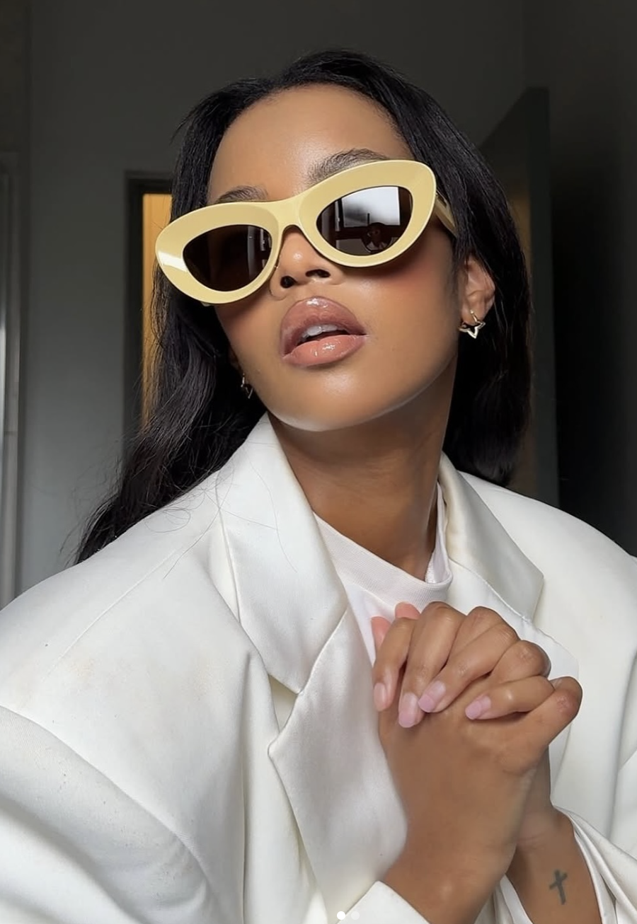 Woman wearing sharp geometric cat-eye sunglasses with thick white frames, a top eyewear trend for 2026.