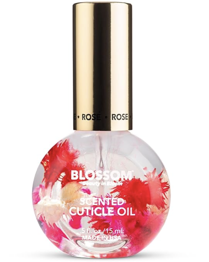 A round glass bottle of Blossom Scented Cuticle Oil containing real pink dried flowers and a gold cap, shown on a transparent background.