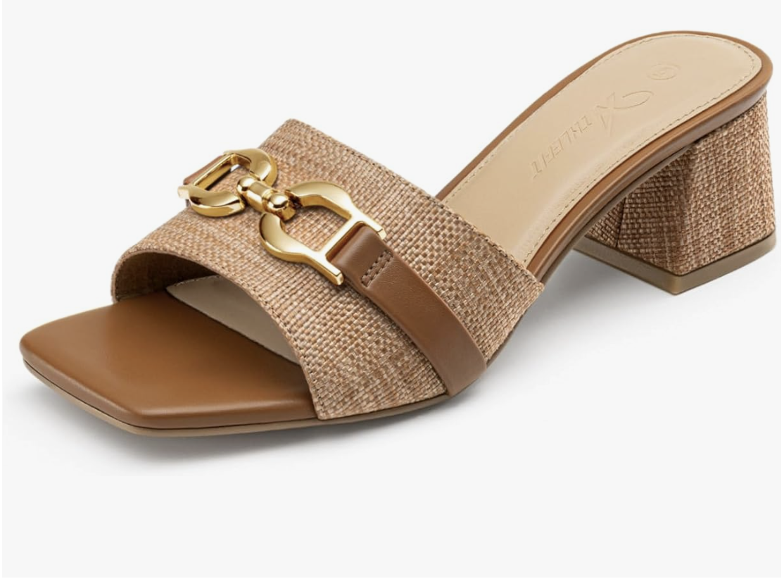 A pair of tan raffia-textured slide sandals with a low block heel and a gold chain-link buckle detail, perfect for a comfortable spring capsule wardrobe for women in their 60s.
