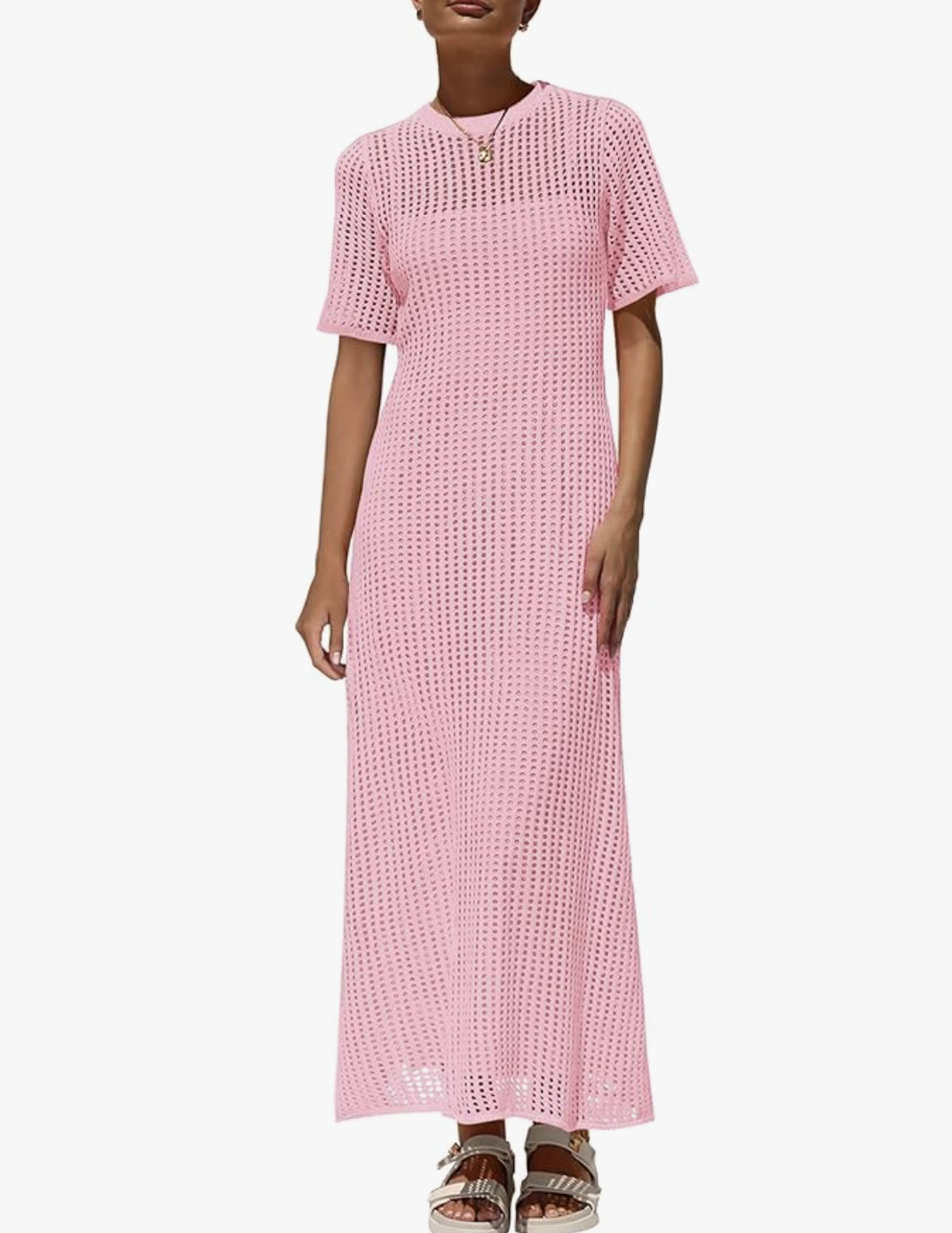 A woman wearing a sleeveless, ankle-length light pink eyelet crochet knit maxi dress swimsuit cover-up paired with platform sandals.