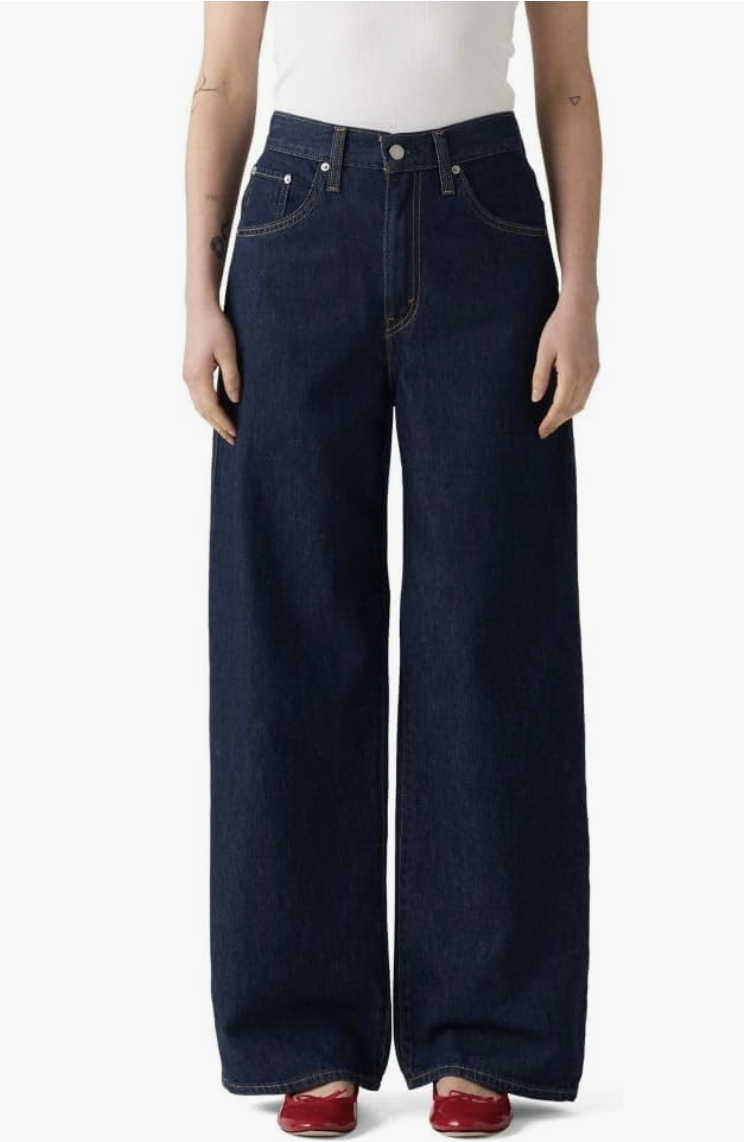 A product shot of dark wash Levi's Cinch Baggy wide-leg jeans paired with red ballet flats, demonstrating an editor-approved way to balance a relaxed denim silhouette with a pop of color.