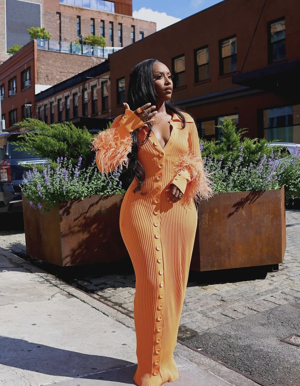 A woman in a cream-colored knit sweater dress and tall brown leather boots.