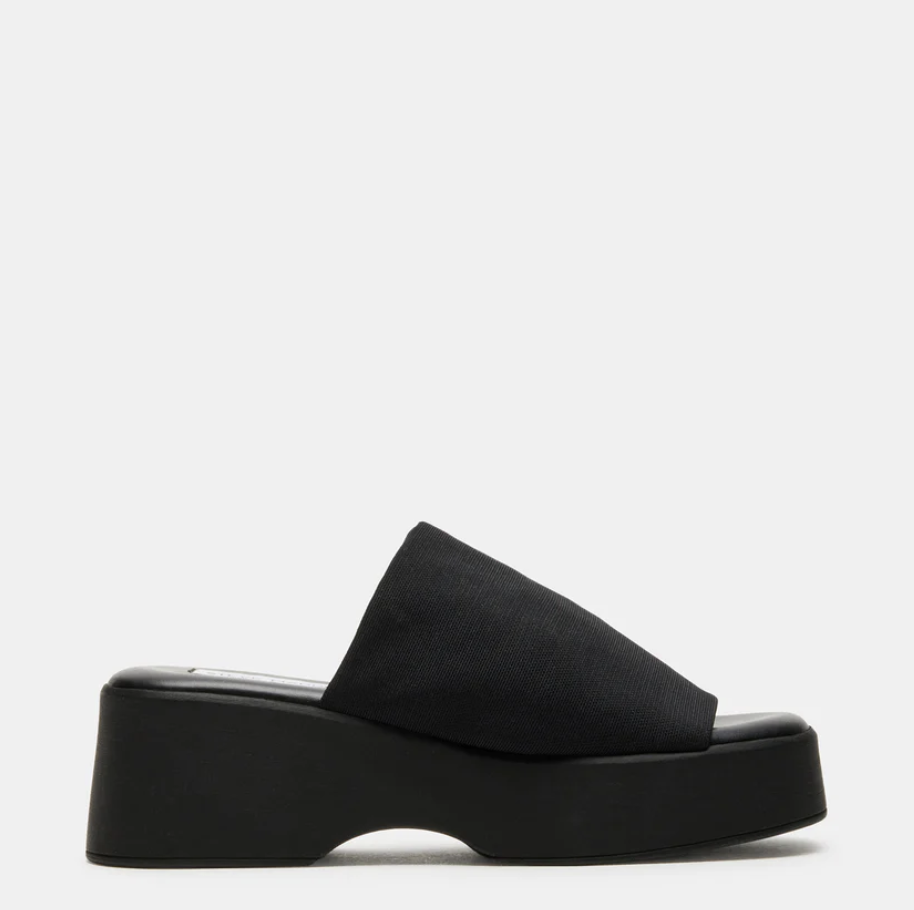 A pair of Steve Madden Slinky30 black platform slide sandals with a thick 90s-style flatform sole and a stretchy fabric upper.