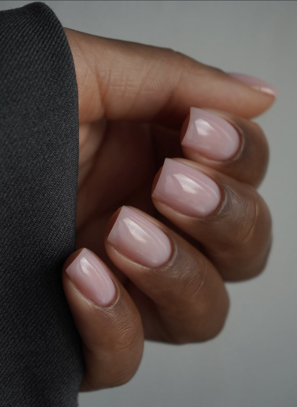 Close-up of short, squoval nails painted in a glossy dusty rosewood pink polish.