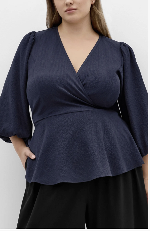 City Chic Celina wrap top with a V-neck, peplum hem and billowy sleeves.
