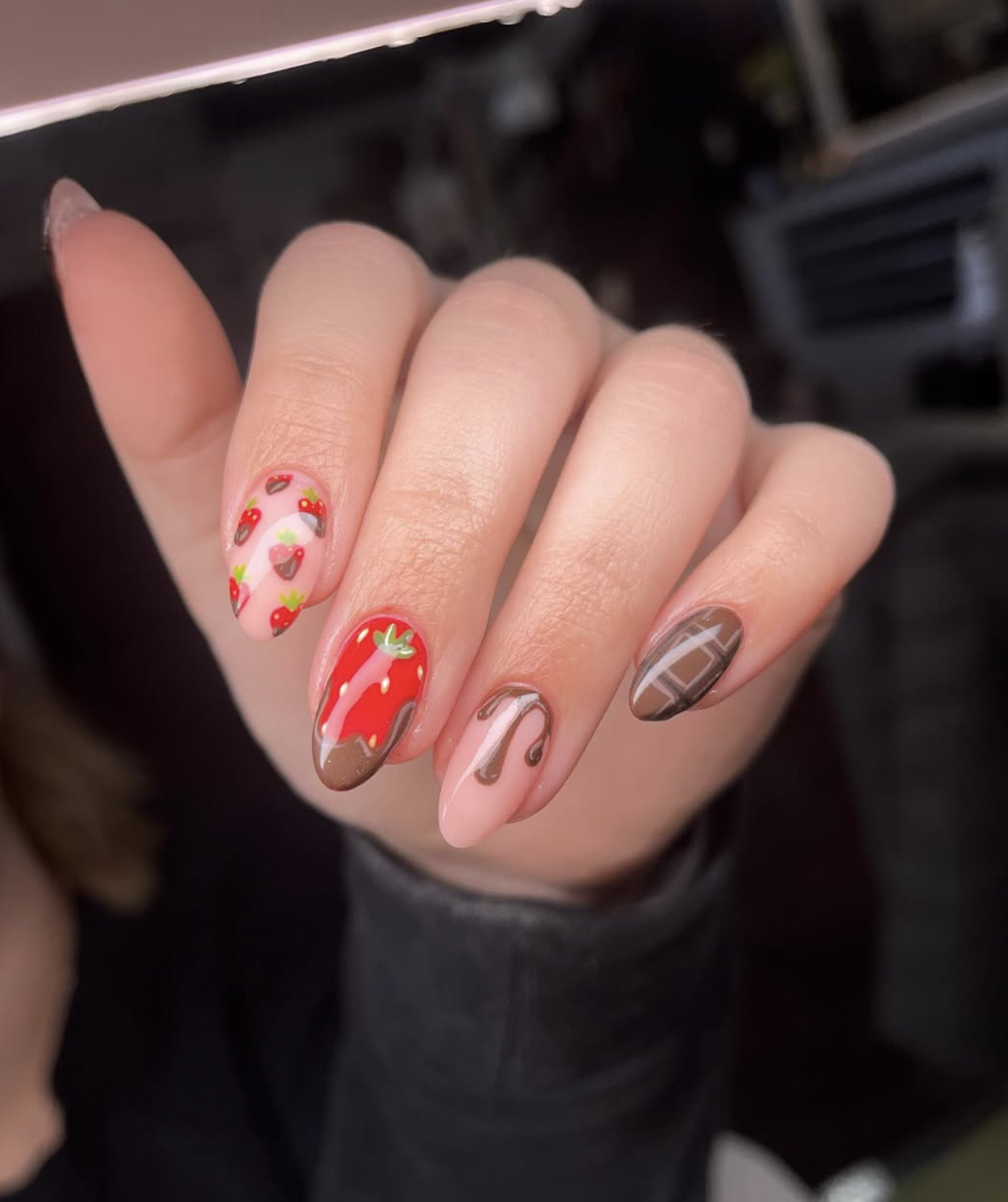 Oval strawberry-red nails with curved chocolate-brown sections across the tips.