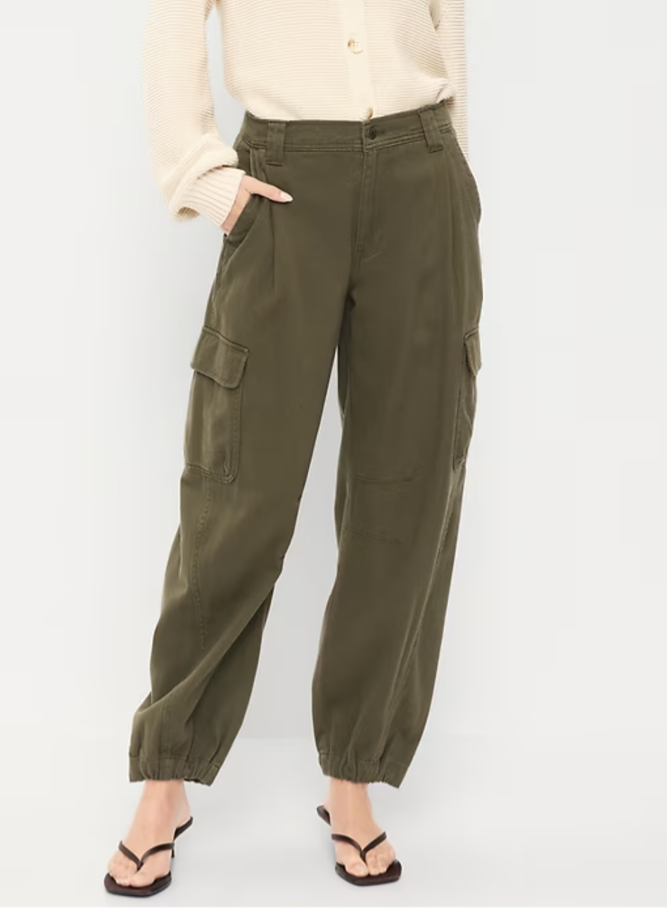 Woman wearing olive green high-rise barrel cargo pants with front patch pockets and black thong sandals.