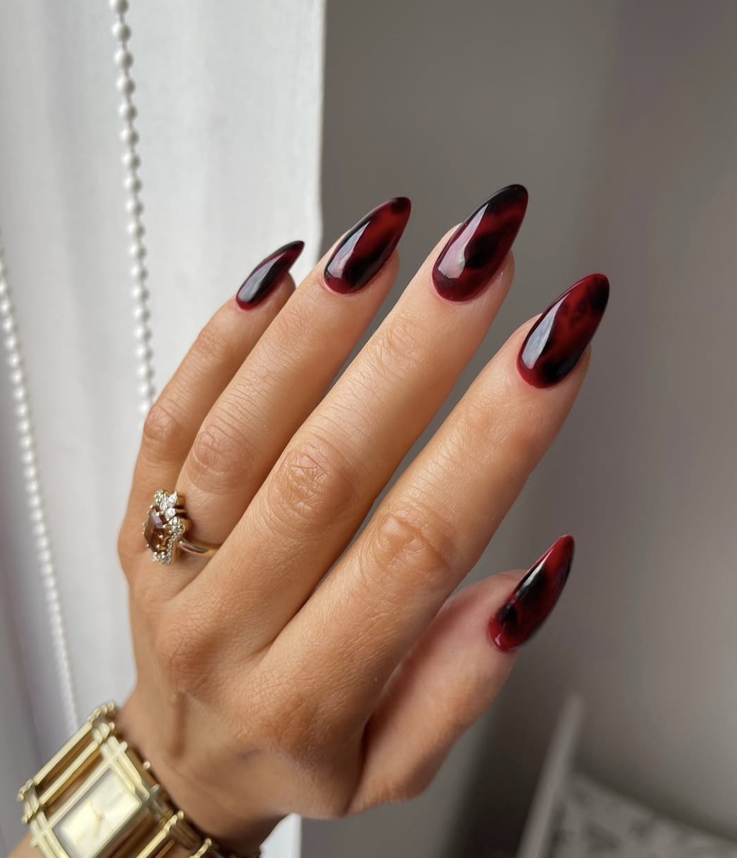 Long almond-shaped gel nails in a deep, glossy dark cherry burgundy finish.