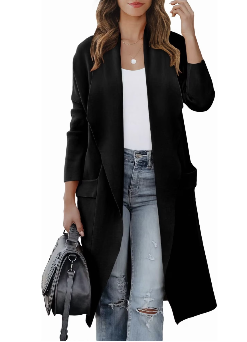 Woman wearing a long black open-front knit cardigan over a white tank and light-wash jeans, carrying a black leather bag.