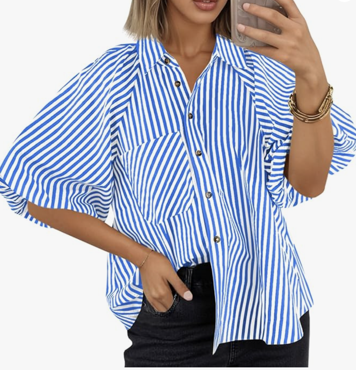 A close-up of a woman wearing an oversized blue and white vertically striped button-down shirt with voluminous sleeves, tucked into black denim jeans.