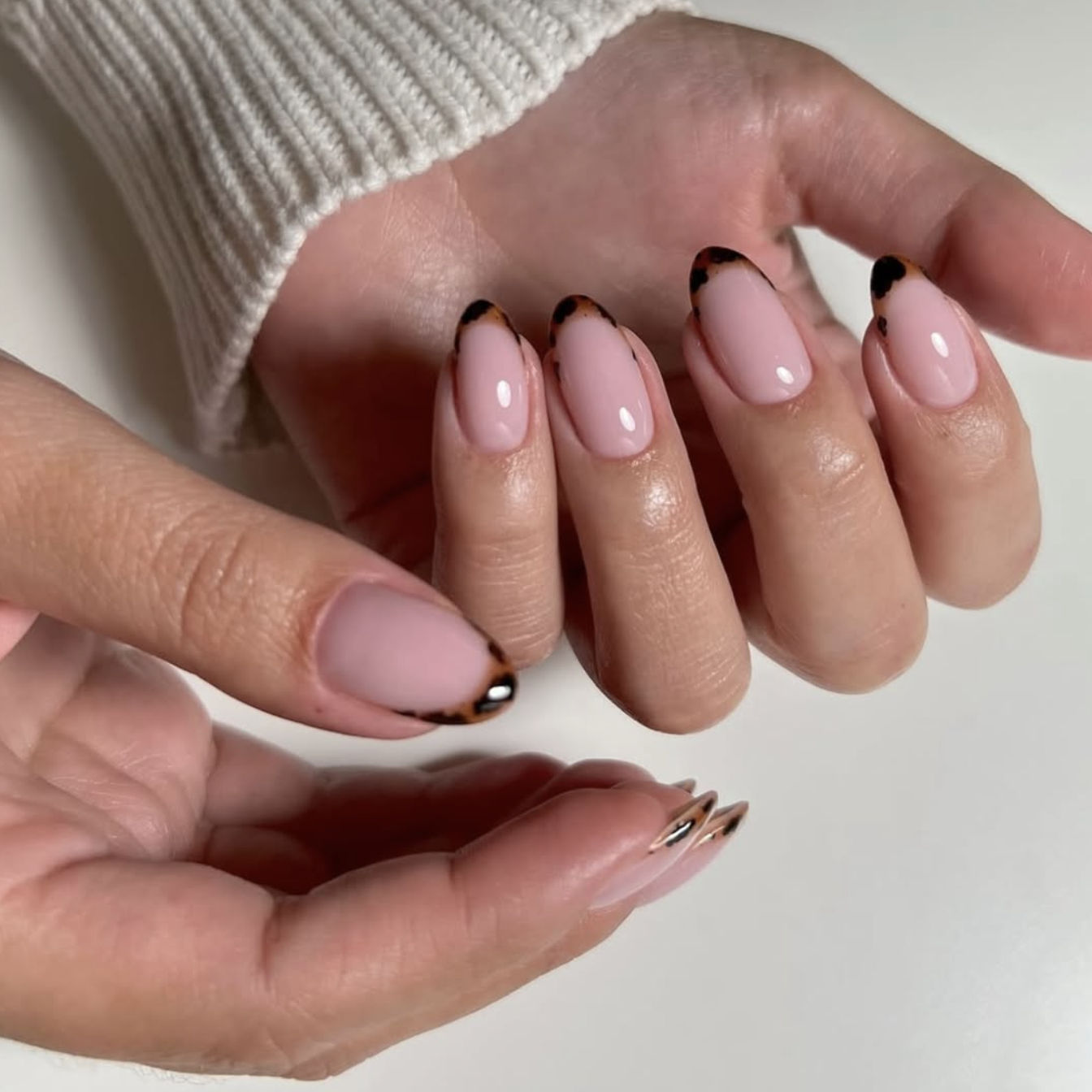 Long almond-shaped nails with a nude BIAB base and semi-translucent tortoiseshell French tips in shades of amber and black.