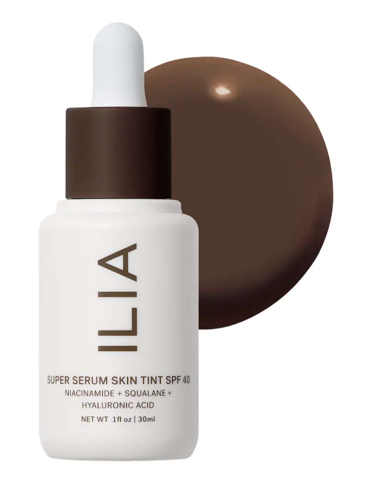 A bottle of Ilia Super Serum Skin Tint SPF 40 with a smooth swatch of hydrating liquid makeup foundation behind it.