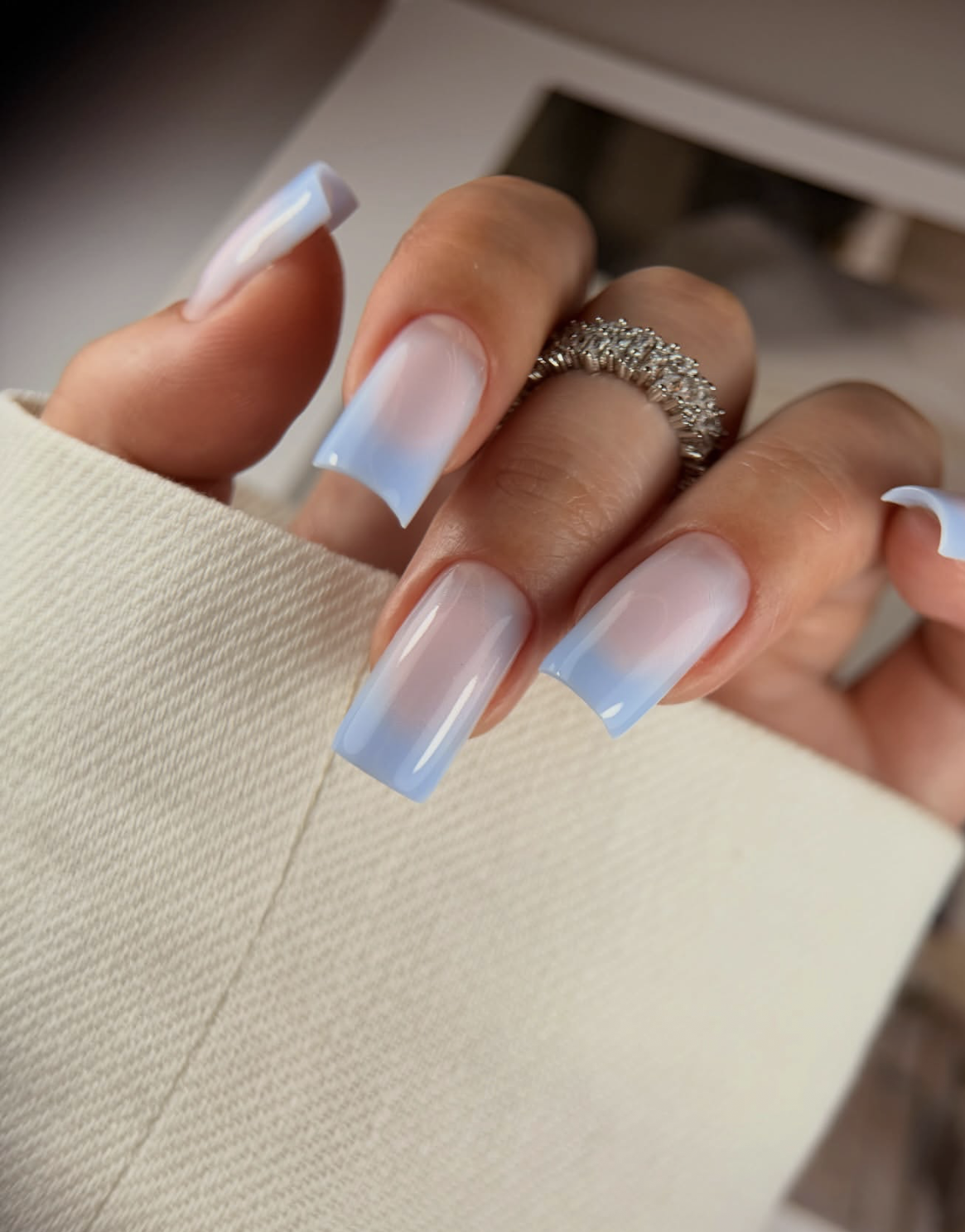 Long, square-shaped nails with a glossy, semi-sheer baby blue base coat topped with a radiant silver chrome glaze finish.
