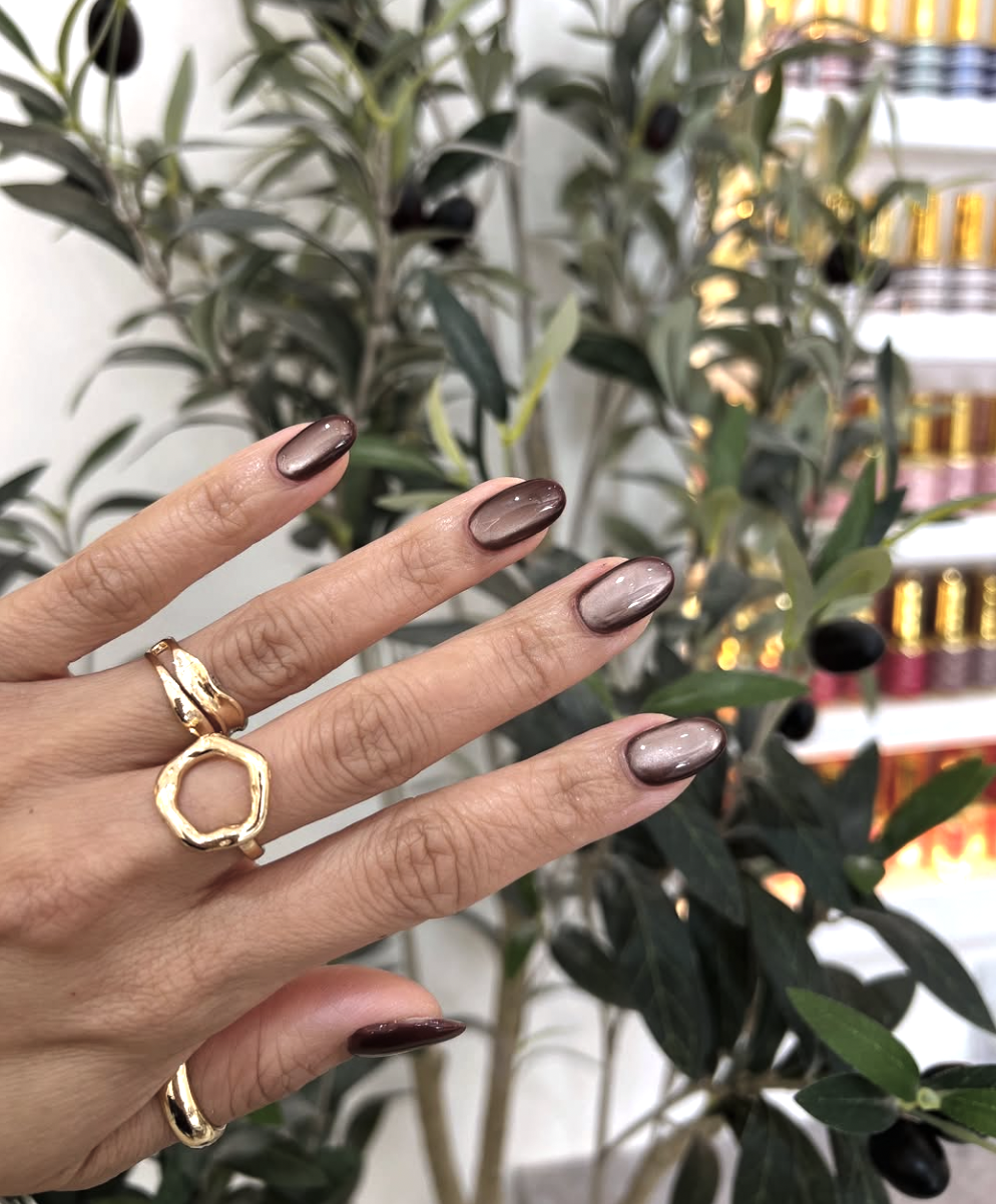 2026 nail trends: Sophisticated oval shaped nails with a high-shine finish and gold jewelry accents.