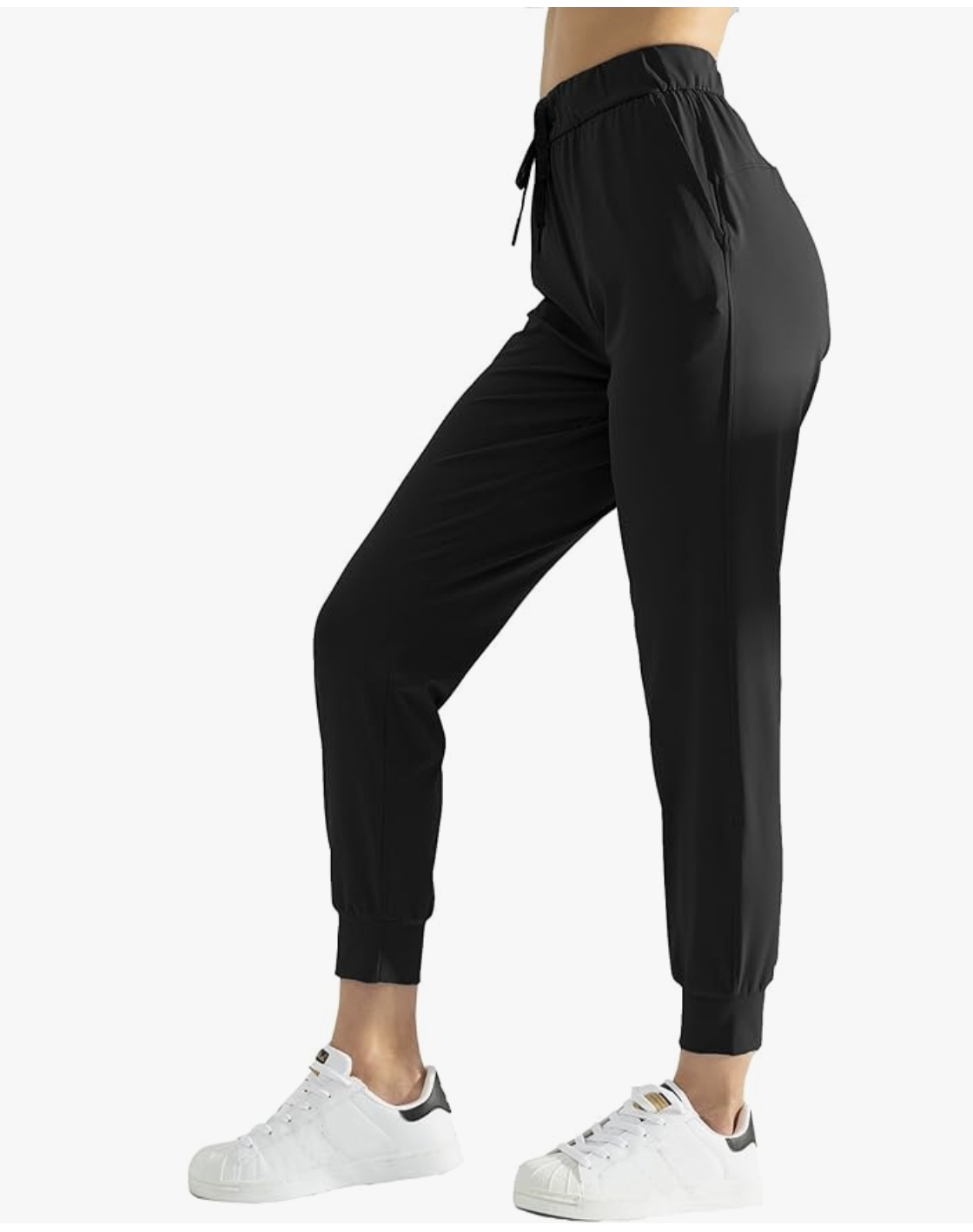 A person wearing black tapered jogger pants with elastic cuffs, paired with white low-top sneakers for a modern casual look.