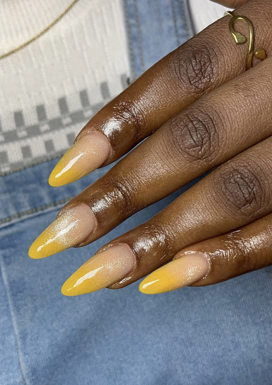 A sunset-inspired yellow aura manicure on long almond nails, featuring a soft gradient effect for summer 2026.