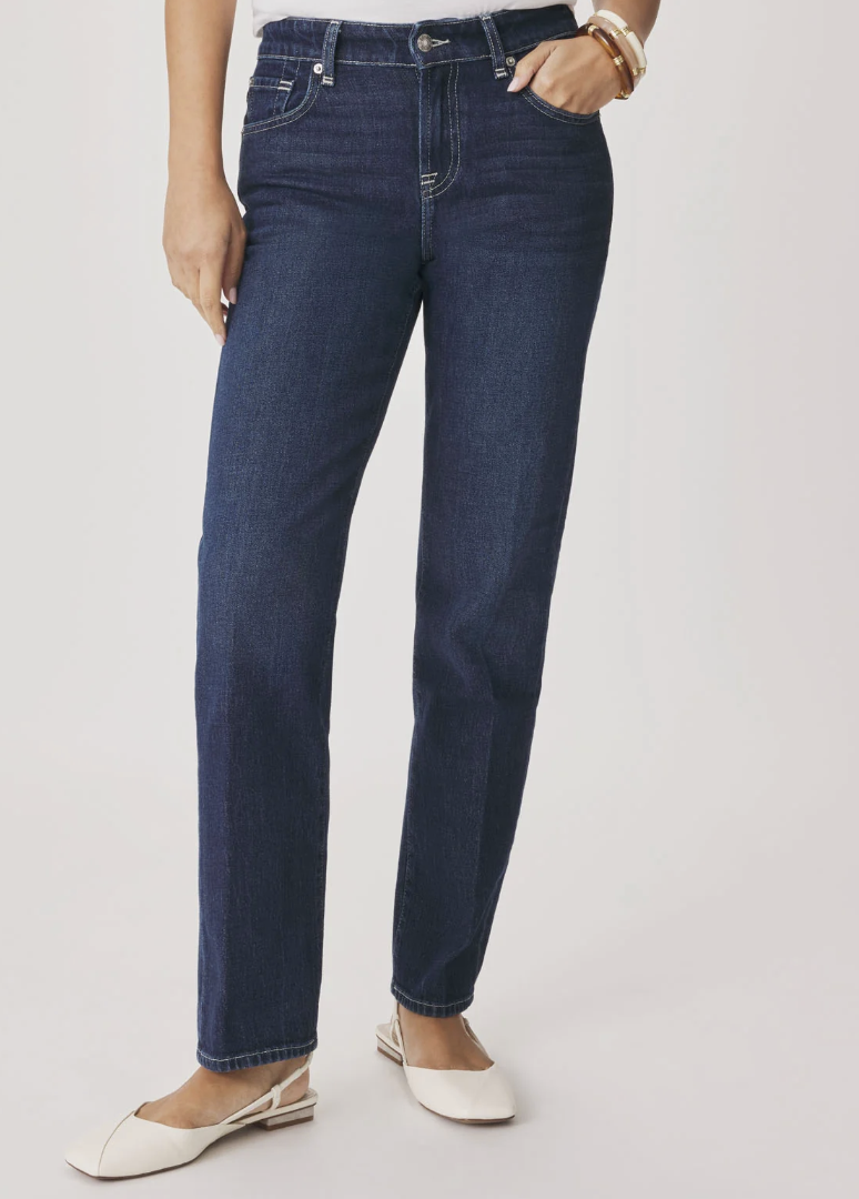 Close-up of high-waisted dark wash straight-leg jeans with a cuffed hem, styled with a white top and a delicate gold bracelet.
