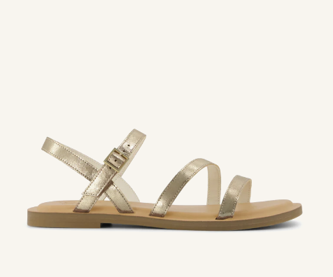 TOMS Women's Kira Leather Sandals in metallic gold featuring a minimalist strappy design, adjustable ankle strap, and cushioned OrthoLite® Eco X40-Hybrid™ insole.