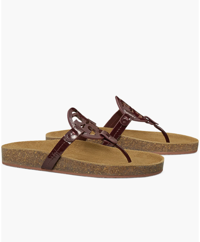 A pair of burgundy patent leather Tory Burch Miller Cloud thong sandals featuring the iconic laser-cut logo and a contoured cork footbed.
