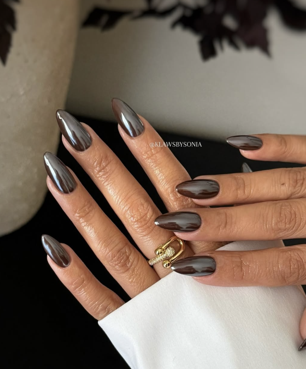 Almond-shaped chocolate-brown chrome nails with a smooth reflective finish.