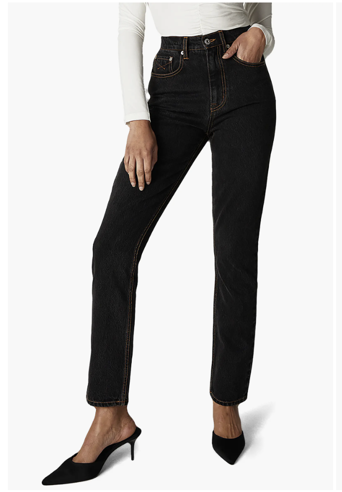 Close-up of a woman wearing high-waisted black cigarette jeans and a white long-sleeve top.