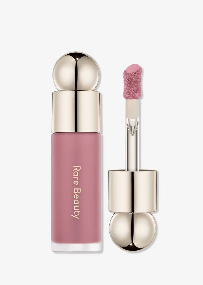 Rare Beauty Soft Pinch Liquid Blush in the shade Believe, showing the mauve-berry liquid formula on the applicator alongside the signature gold-capped bottle.