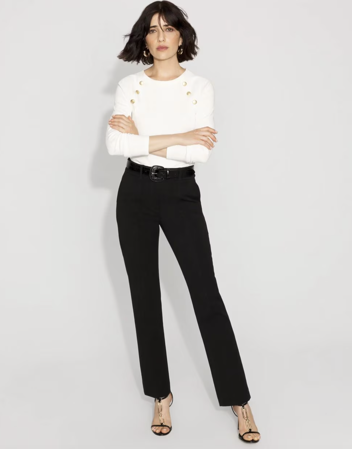A woman wearing black high-rise straight-leg pants and gold-detailed heels, showcasing a timeless and intentional workwear look.