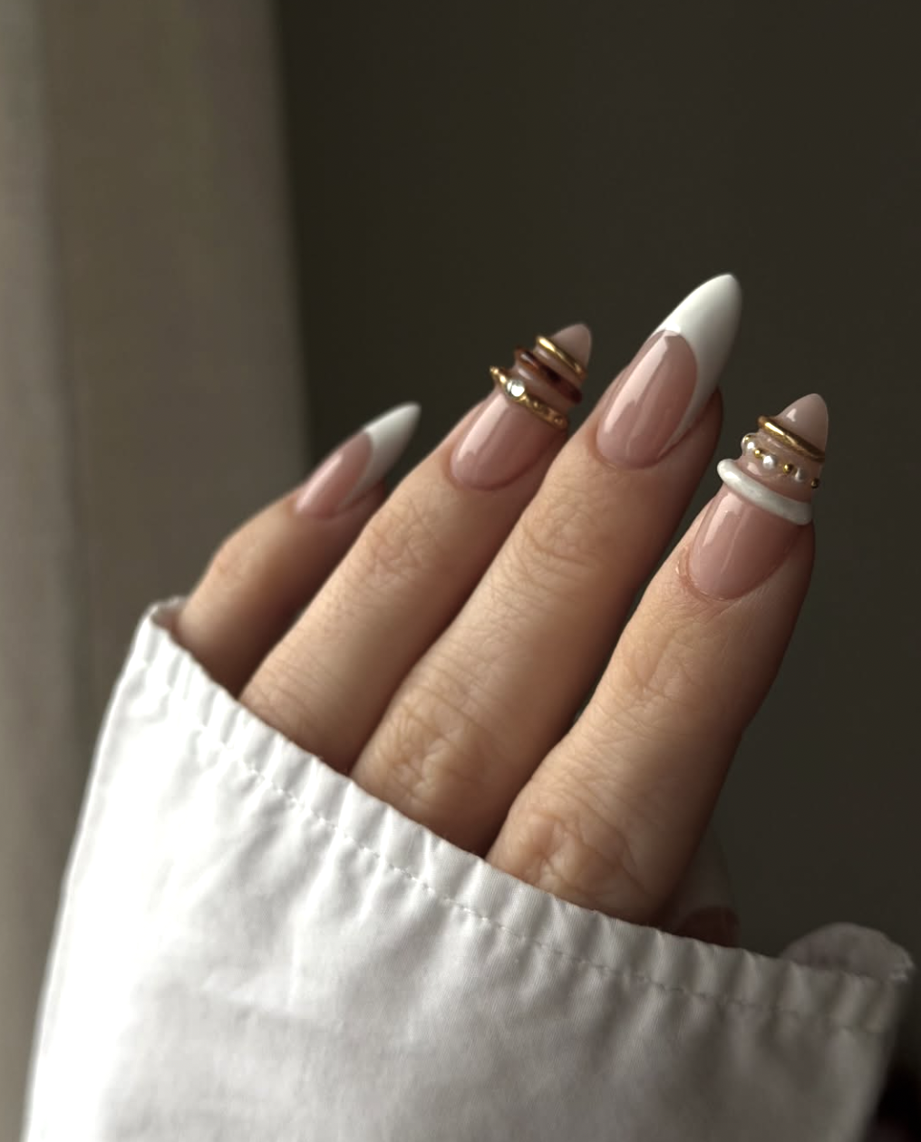 Almond-shaped milky white nails with textured 3D silver bangle bands and frosted metallic accents.