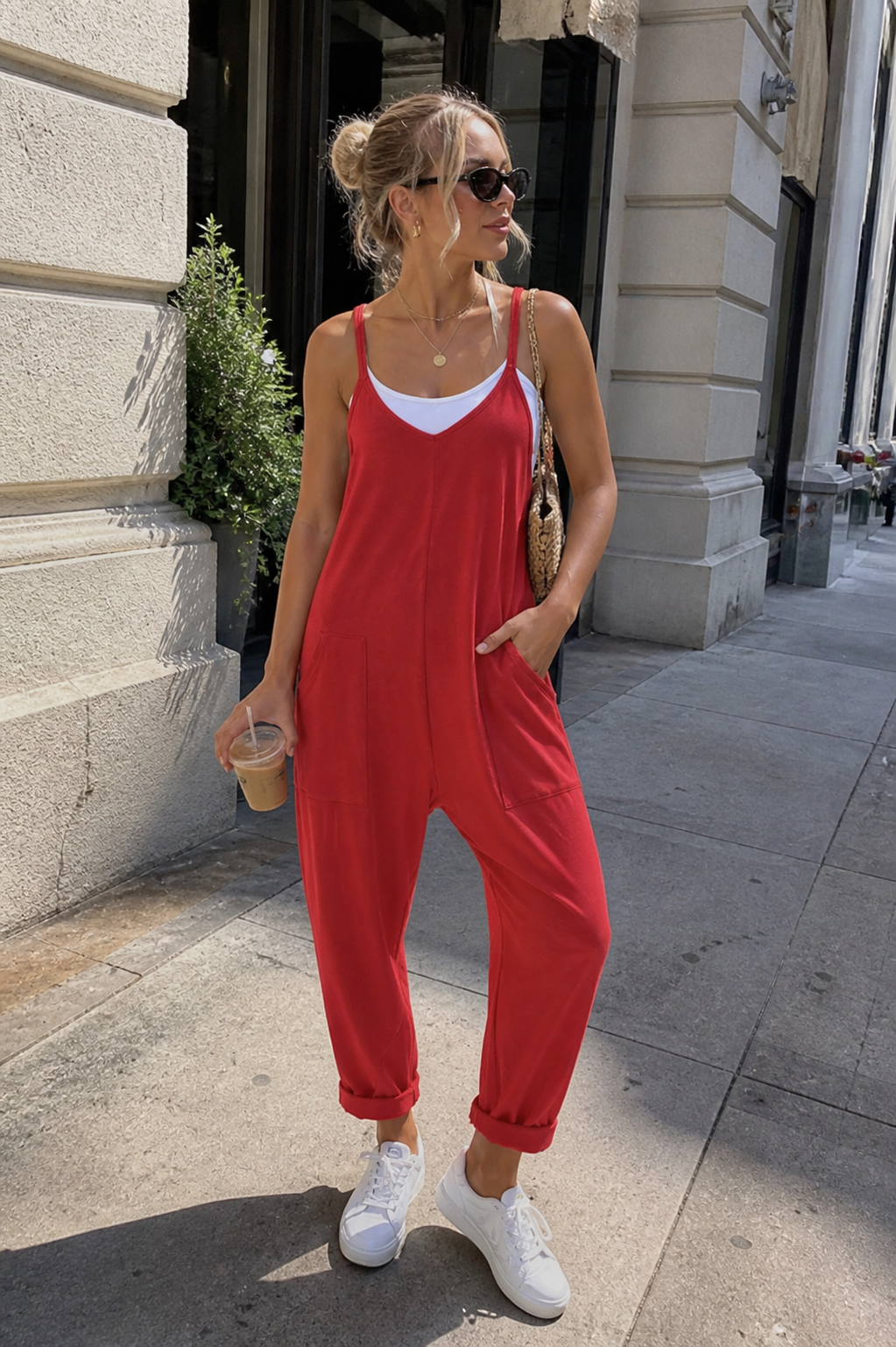 Fashion editor wearing a bright red oversized Hot Shot onesie jumpsuit over a white tank top, demonstrating a 2026 casual athleisure outfit formula.