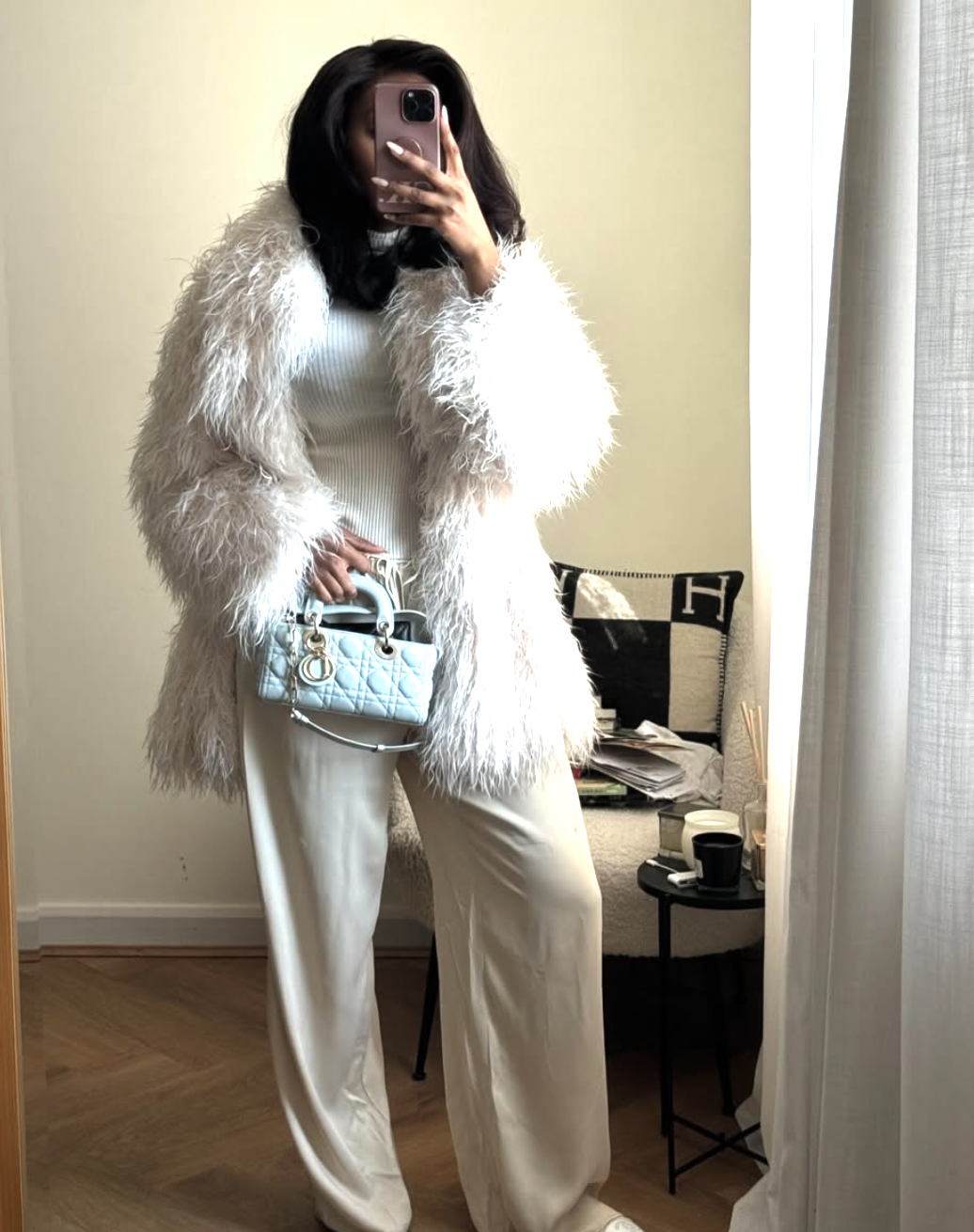 high-low street style lookbook image of a woman wearing a white t-shirt layered under a voluminous white faux fur coat and paired with cream satin wide-leg trousers.