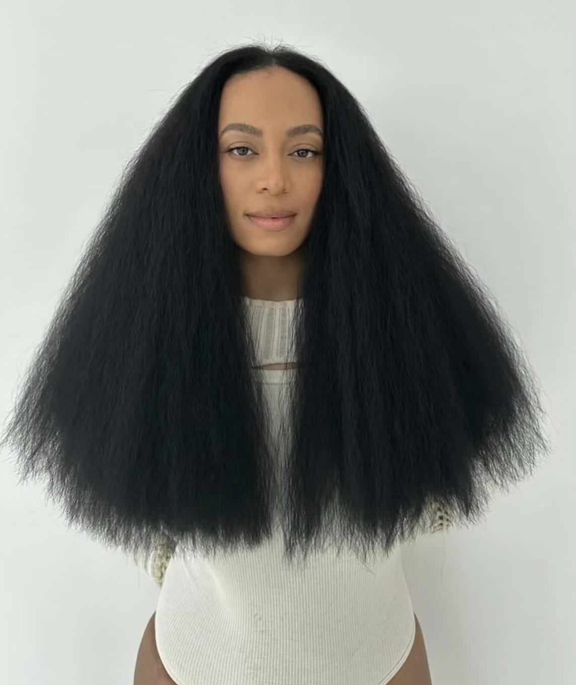 Solange Knowles wearing a full, rounded natural afro that complements the balanced proportions of an oval face shape.