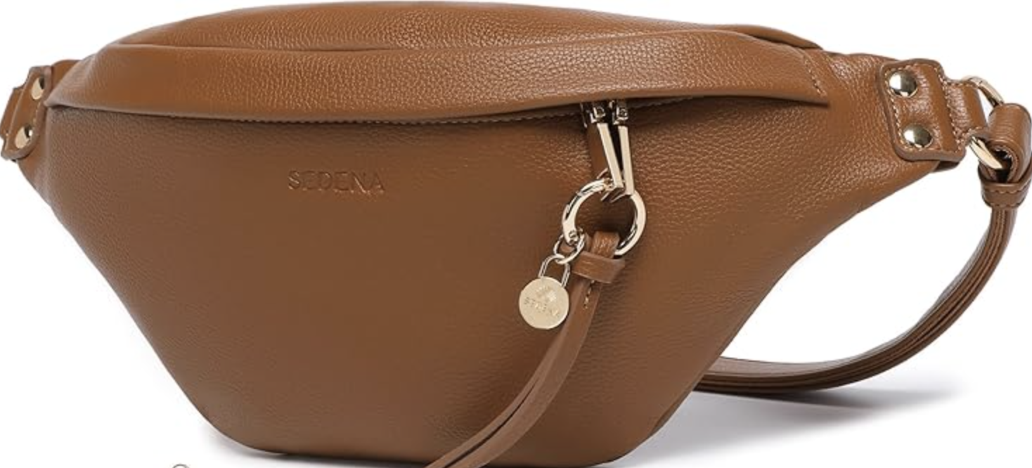 A tan Baggallini Everywhere crossbody travel bag with multiple silver-zippered pockets and a wide adjustable strap, styled as a functional and organized accessory for women in their 60s.