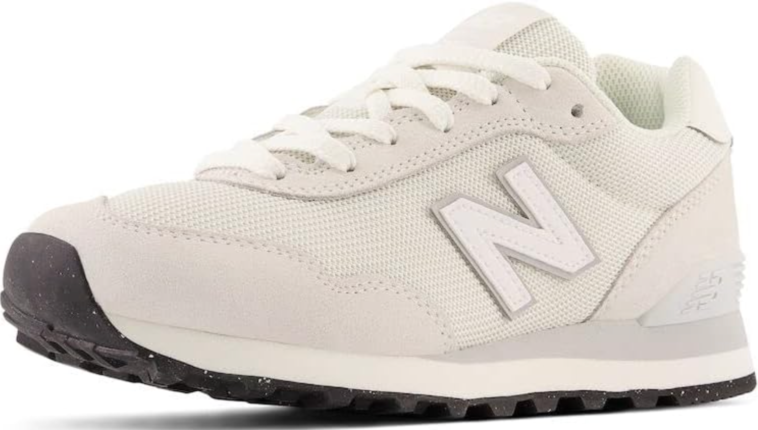 A close-up side view of an off-white New Balance 574 sneaker featuring a light grey classic "N" logo and a speckled dark grey outsole.