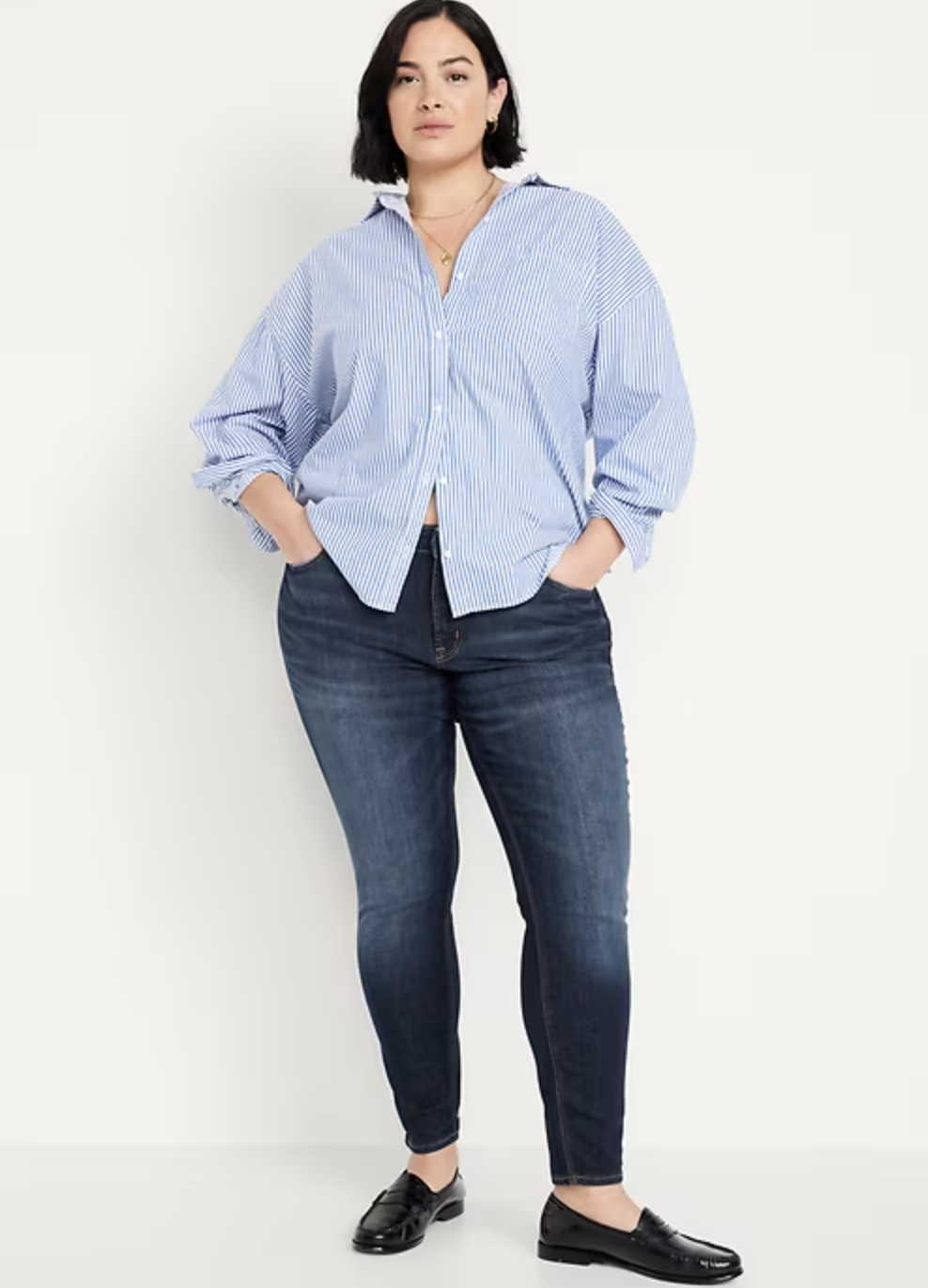 Model wearing Old Navy Mid-Rise Rockstar Super Skinny Jeans in a dark wash, featuring 360-degree stretch denim that contours to muscular legs and an athletic build, styled with black loafers.