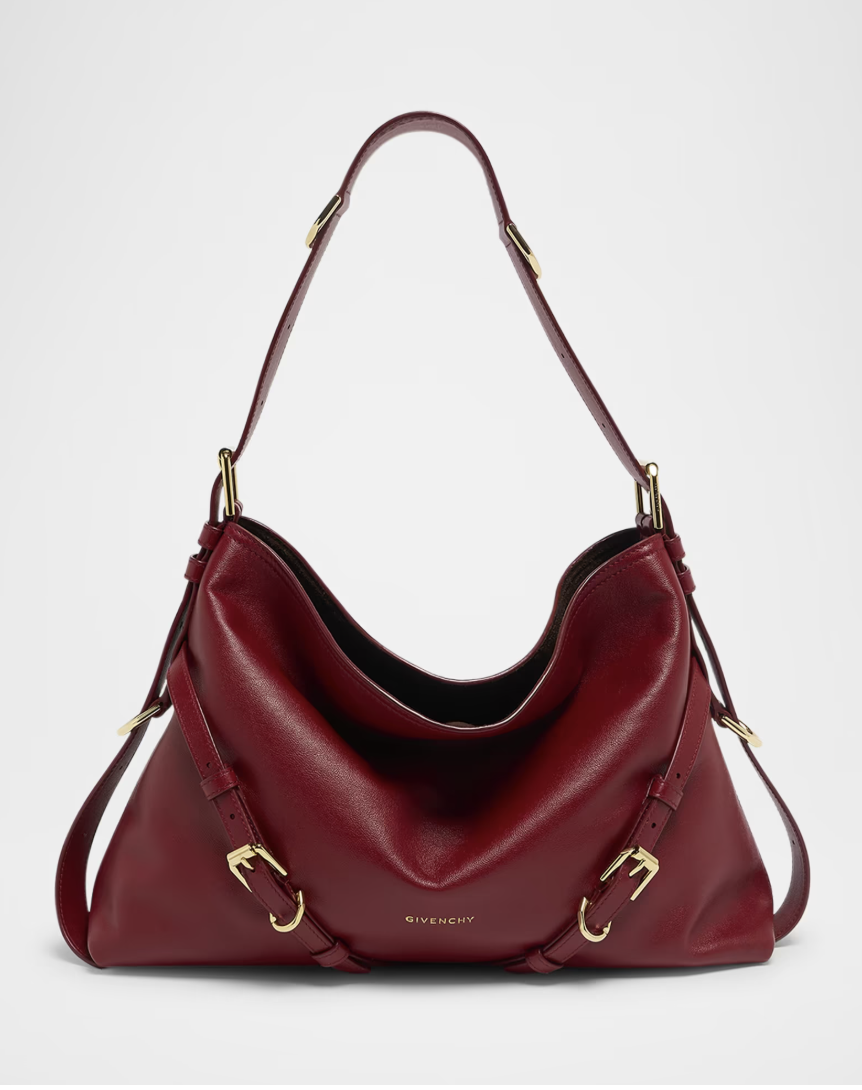 A slouchy deep burgundy leather shoulder bag with a curved silhouette, shoulder strap, and subtle gold hardware details.