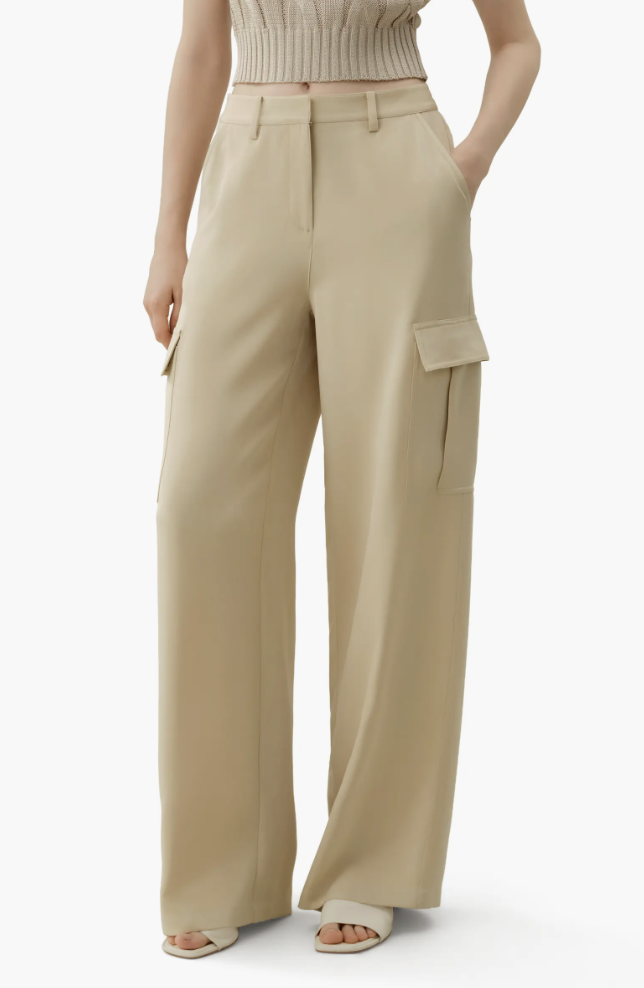 A person wearing high-waisted beige wide-leg cargo pants with large side utility pockets and cream-colored thong sandals.