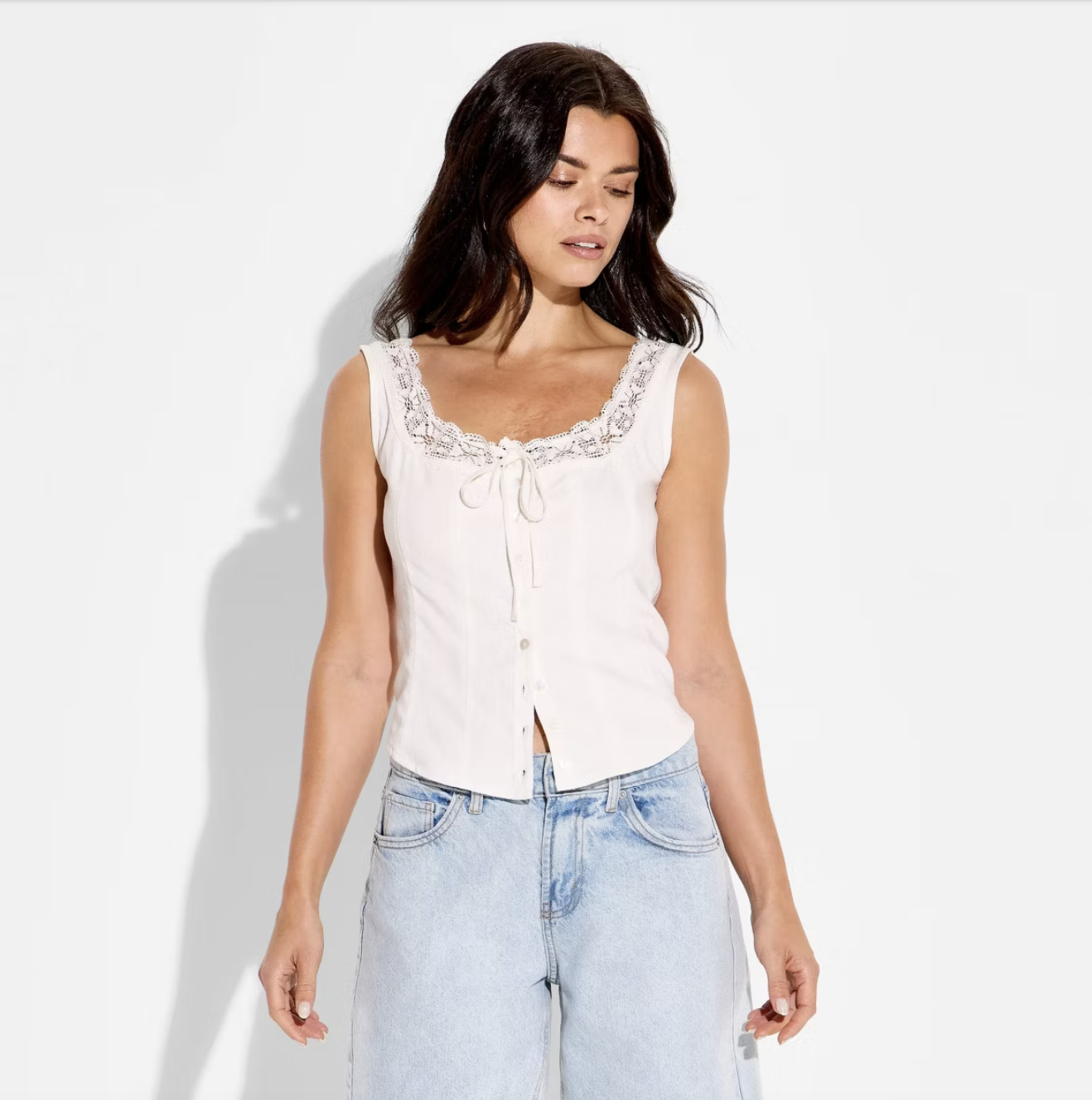 A woman wearing a white Wild Fable eyelet tank top with a button-front and lace trim, styled with light-wash jeans for a Spring 2026 outfit.