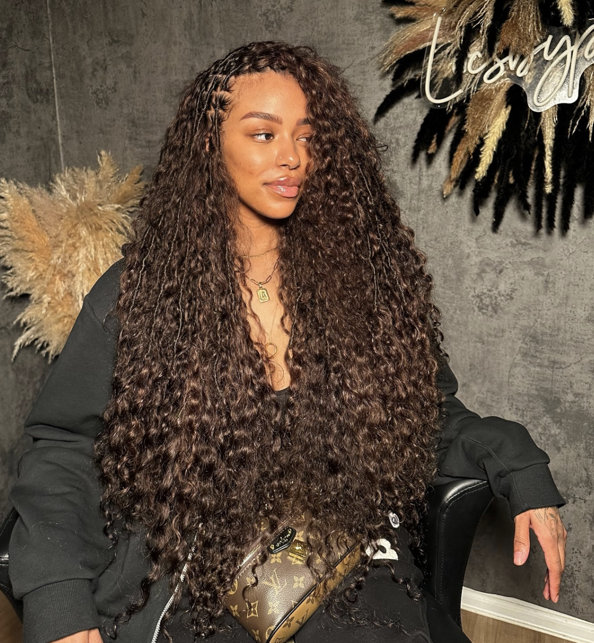 A woman with a square face shape wearing long, textured goddess locs that fall past the shoulders to create a soft framing effect around a defined jawline.