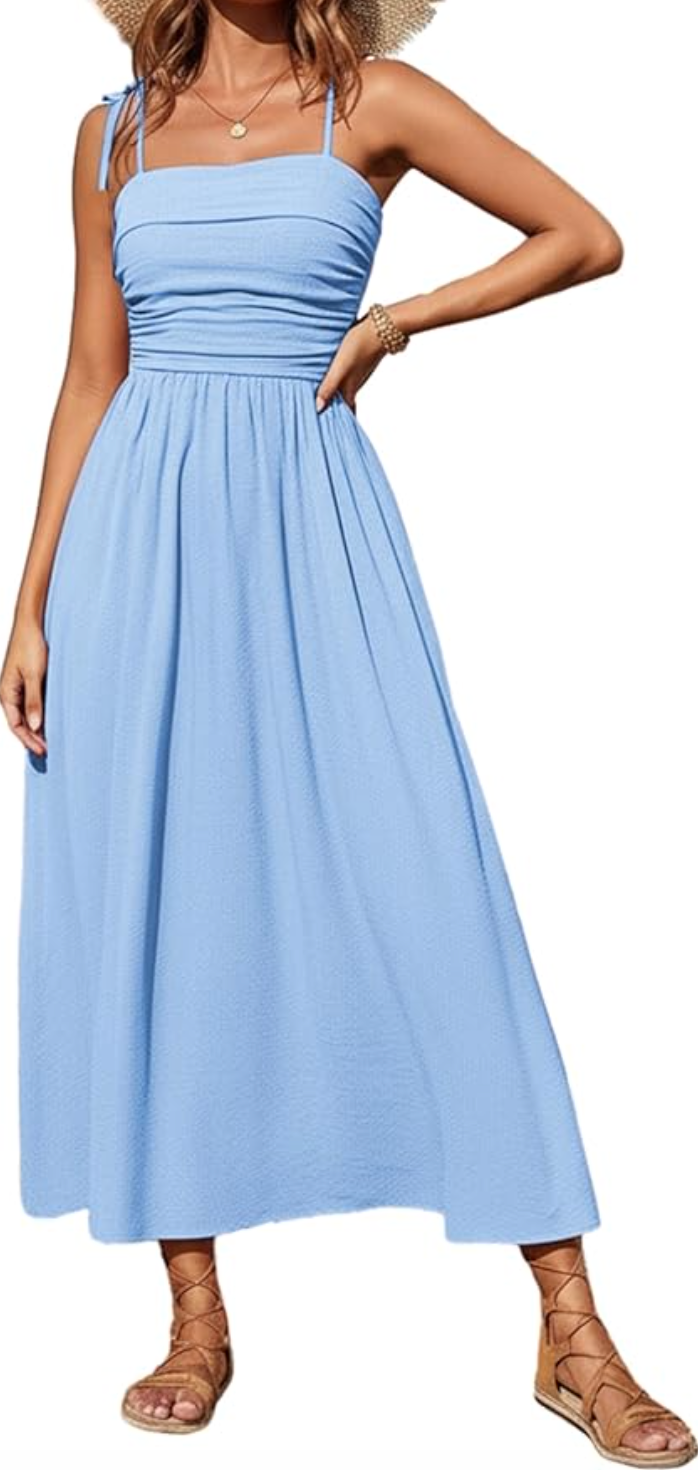 A woman wearing a cornflower blue spaghetti strap maxi sundress with a flowy tiered skirt and lace-up gladiator sandals.